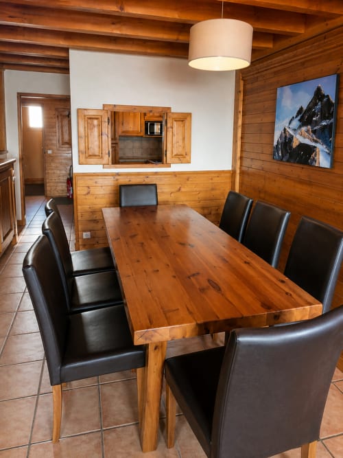 Salle à manger avec table en bois et chaises noires au Chalet des Cimes, Savoie