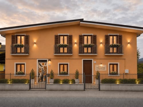 Stella CasaBono hotel in Sulmona with illuminated terracotta facade, shuttered windows, and flower-adorned balconies at dusk