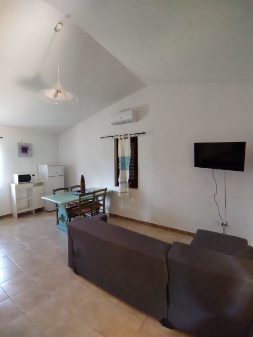 Spacious living area in San Teodoro villa with dining table, sofa, wall-mounted TV, and modern furnishings