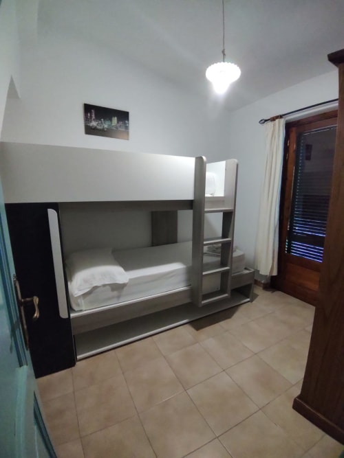 Modern bunk bed in bright villa bedroom with tiled floor, pendant light, and wooden door at Holidays San Teodoro