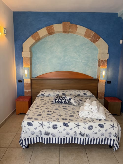 Camera matrimoniale a Villa Arneide con alcova ad arco, biancheria a tema marino e mobili in legno