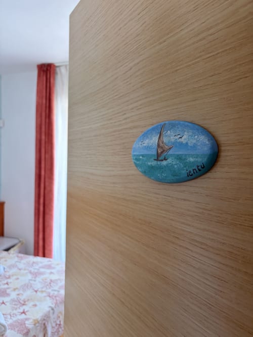Targa costiera ovale blu con barca a vela su parete in legno nella camera del B&B Torre Lapillo