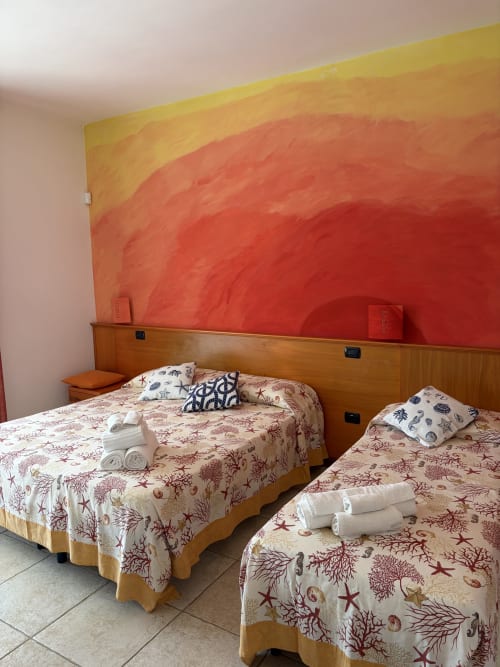 Luminose camere gemelle con biancheria nautica alla B&B Villa Arneide, Torre Lapillo, testiera murale vivace