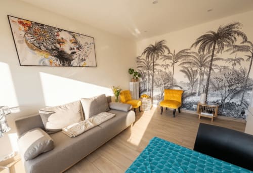 Salon moderne avec canapé beige, touches jaunes, papier peint tropical et vue sur le jardin à Conciergerie IB