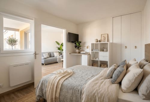 Chambre moderne avec lit confortable, espace séjour ouvert, rangements blancs et vue sur le jardin de l'appartement Conciergerie IB