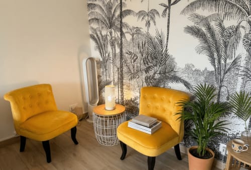 Élégant coin séjour avec vue jardinage, fauteuils en velours jaune, fresque tropicale et purificateur d'air moderne à la Conciergerie