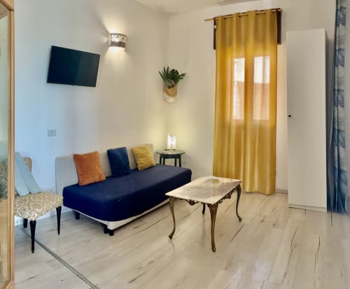 Bright apartment living room with sofa, TV, and marble table at Noemi Holiday House, Agnone Bagni