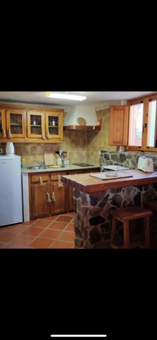 Cozinha clara com armários de madeira, azulejo verde, ilha e piso vermelho no T Monte B&B Porto Côvo