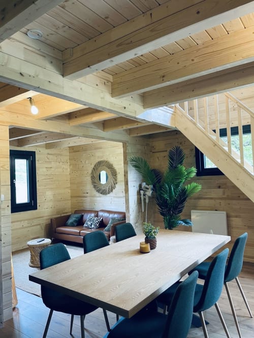 Modern wooden lodge interior with dining table, leather sofa, and potted plant at Cabanes et lodges du Belvédère,