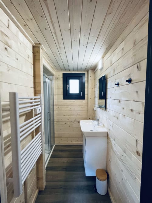 Modern wooden bathroom in Lodge Hibiscus villa with sink, toilet, heated towel rail, and dark doors at Cabanes et lodges du