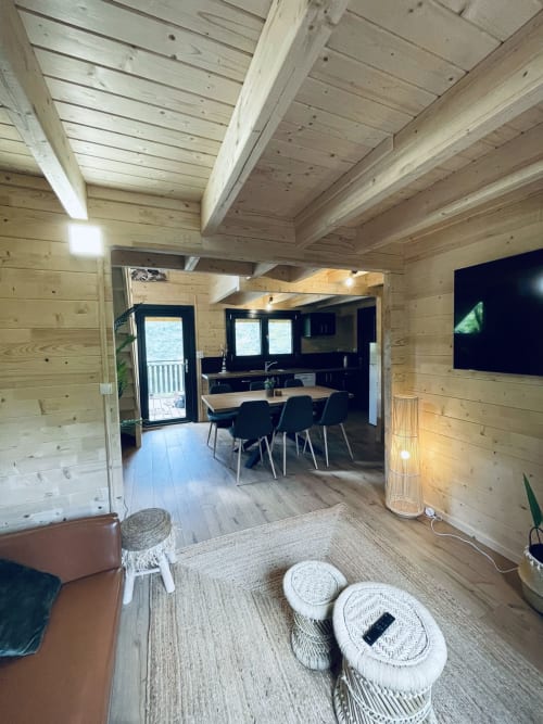 Modern wooden lodge interior with dining area, kitchen, and living room at Cabanes du Belvédère, Serrières-sur-Ain