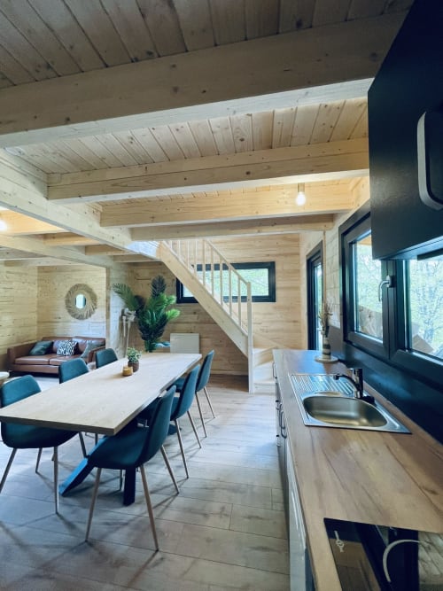 Interno di lodge in legno moderno con sala da pranzo, cucina e zona living affacciata sul lago Serrières-sur-Ain