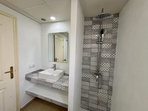 Baño moderno con ducha de azulejos con patrón y lavabo blanco en el hotel Plus Costa Brava en L'Estartit
