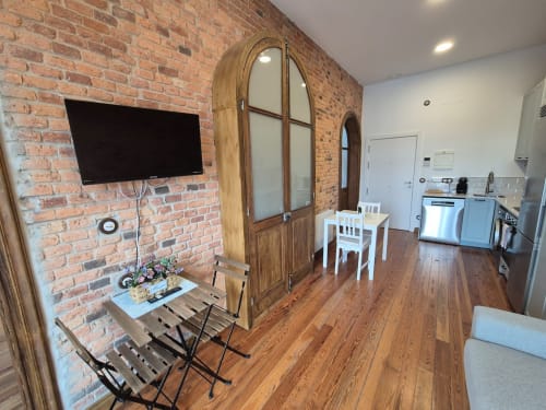 Apartment 3-Juan Pinto at Fabrica de Atardeceres: living area with brick wall, TV, wooden wardrobe, dining table, and kitchen