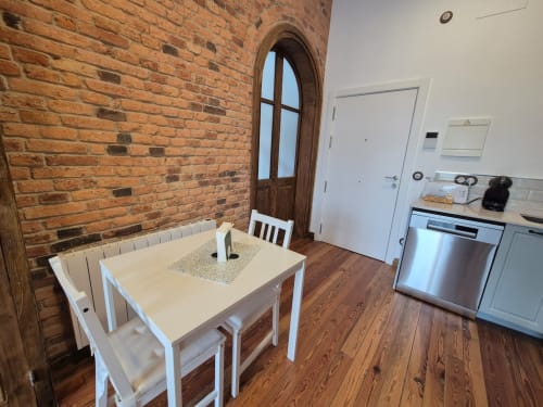 Modern kitchen-dining area at Fabrica de Atardeceres apartment with brick walls, white table, and stainless steel appliances