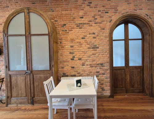 Juan Pinto apartment at Fabrica de Atardeceres featuring arched wooden doors, brick walls, white dining table and chairs