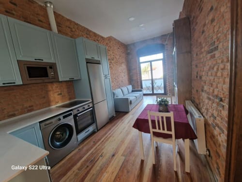 Modern kitchen-living area at Fabrica de Atardeceres apartment 3-Juan Pinto with exposed brick, dining table, and sofa