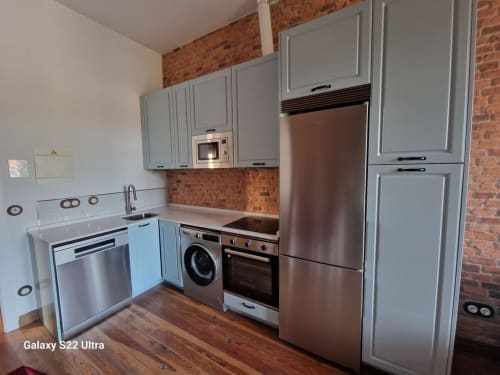 Modern kitchen in Juan Pinto apartment at Fabrica de Atardeceres with gray cabinets, stainless steel appliances and exposed