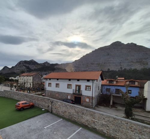 Fabrica de Atardeceres hotel with terracotta-roofed buildings, orange car, and mountain backdrop in Spain