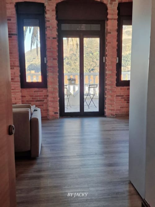 Interior moderno del apartamento en Fabrica de Atardeceres con muros de ladrillo, puertas oscuras que abren a terraza con vista a la montaña