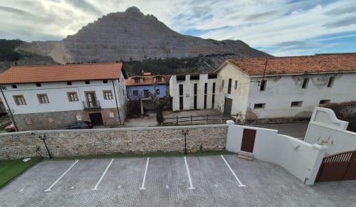Zona de estacionamiento Fábrica de Atardeceres con espacios numerados, cargador para vehículos eléctricos y arquitectura colonial española