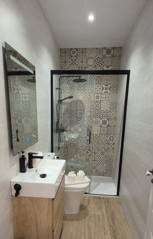 Baño moderno en apartamento Fabrica de Atardeceres con ducha de azulejos decorativos, lavamanos blanco y piso de madera