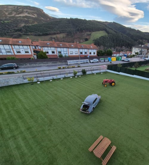 Terrenos de Fabrica de Atardeceres con auto vintage, tractor y mesa de picnic en jardín, montañas al fondo