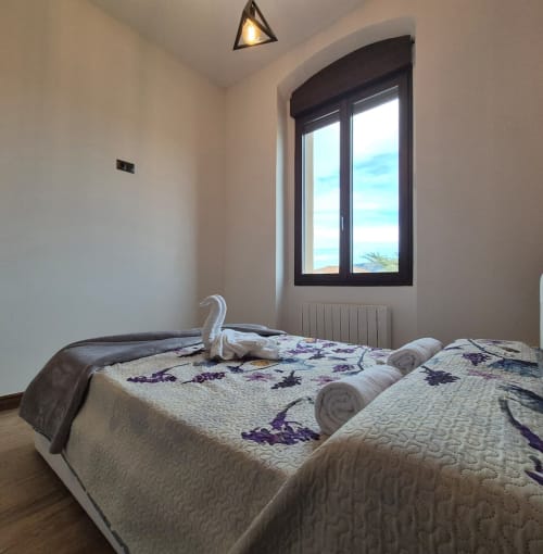 Bright bedroom at Fabrica de Atardeceres with twin beds, sea view window, and modern amenities