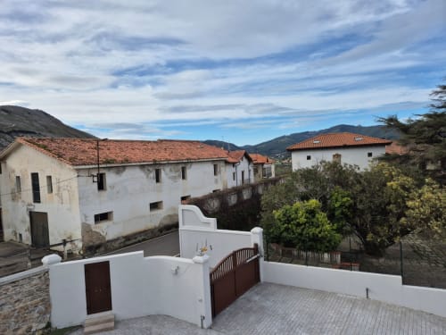 Fabrica de Atardeceres colonial terrace with white walls, dark doors, and mountain views in Spanish countryside