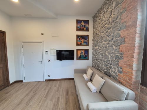 Cozy apartment salon at Fabrica de Atardeceres with beige sofa, exposed stone wall, TV, and framed artwork