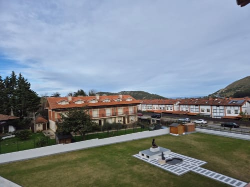 Fabrica de Atardeceres hotel courtyard with solar panels, green lawn, and terracotta-roofed buildings in Spanish mountain