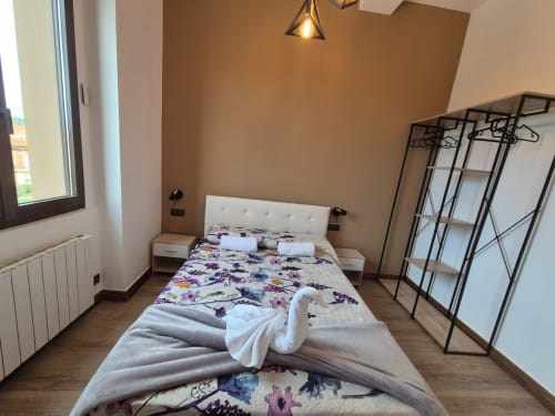 Modern bedroom at Fabrica de Atardeceres with floral bedding, white headboard, black wardrobe, and wooden flooring