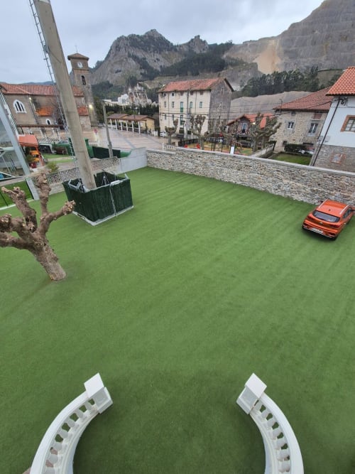 Fabrica de Atardeceres apartment with green courtyard, mountain views, and red car in Spanish village setting