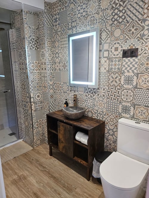 Modern bathroom at Fabrica de Atardeceres with patterned tile walls, dark wood vanity, and illuminated mirror in Manizales