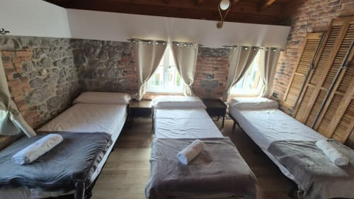 Fabrica de Atardeceres Manizales dormitory with three beds, brick walls, wooden shutters and natural light