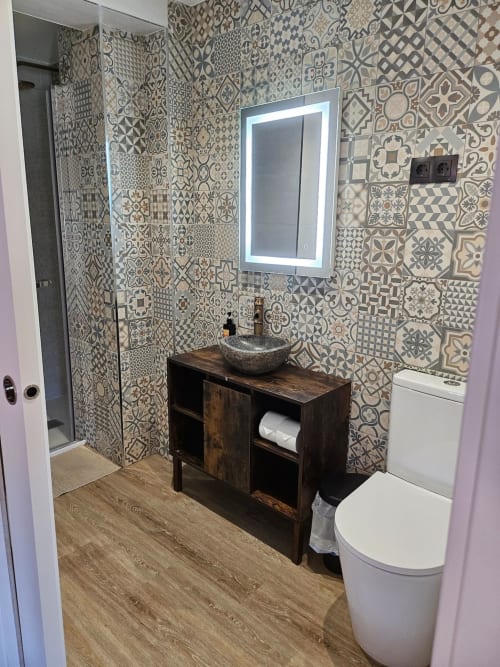 Modern bathroom at Fabrica de Atardeceres with patterned tile walls, vessel sink, illuminated mirror, and wooden vanity.