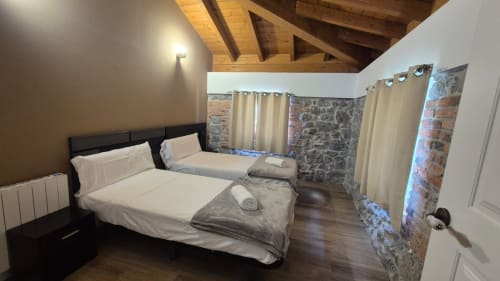 Spacious bedroom at Fabrica de Atardeceres with twin beds, exposed wooden beams, and rustic brick accents in Manizales
