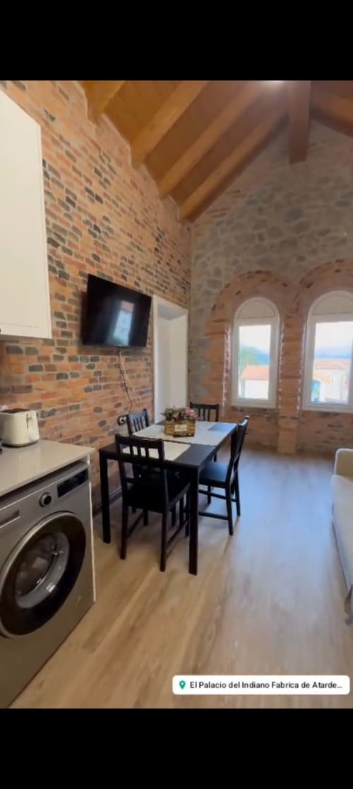 Modern apartment kitchen and dining area with exposed brick walls, wooden beams, and arched windows at Fabrica de Atardeceres