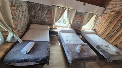 Five single beds in Manizales apartment at Fabrica de Atardeceres, exposed brick walls, cream curtains, wooden shutters