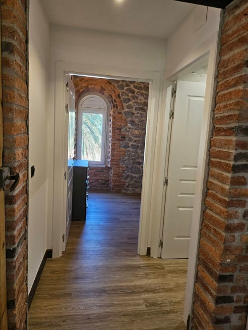Modern hallway with exposed brick walls, white doors, and wooden floors at Fabrica de Atardeceres apartment in Manizales,