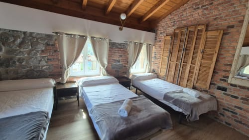 Spacious apartment bedroom at Fabrica de Atardeceres in Manizales with multiple beds, brick walls, and wooden shutters