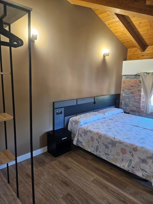 Modern bedroom at Fabrica de Atardeceres with queen bed, black headboard, wooden beams, and shower stall in Barandiaran