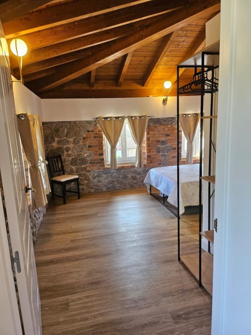 Rustic loft bedroom at Fabrica de Atardeceres with exposed wooden beams, brick walls, metal bunk bed, and natural lighting