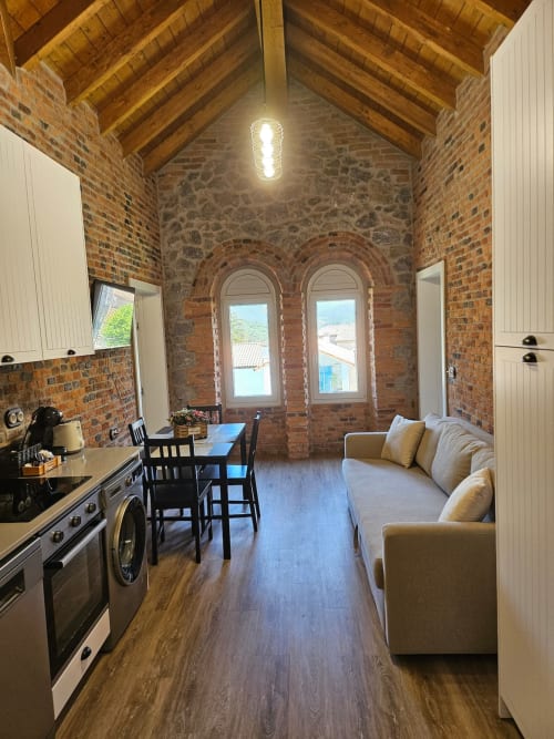 Modern loft apartment at Fabrica de Atardeceres with exposed brick, wooden beams, kitchen, dining area and sofa