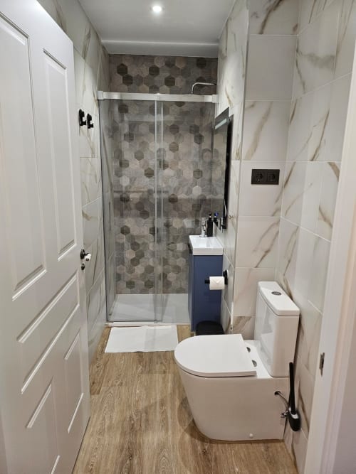 Modern bathroom at Fabrica de Atardeceres apartment with shower enclosure, white fixtures, and marble-style tiles