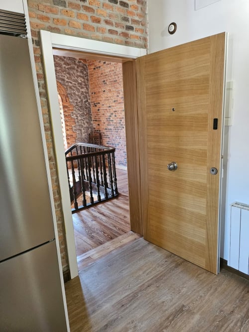 Apartment entrance at Fabrica de Atardeceres with wooden door, brick walls, and view into furnished living space with baby