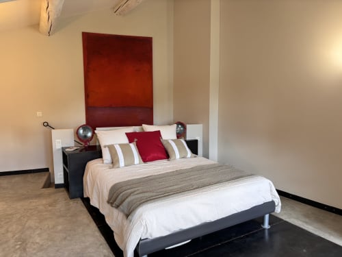 Chambre moderne au Jardin Secret B&B à Grignan avec mur accentué rouge, literie neutre et mobilier contemporain