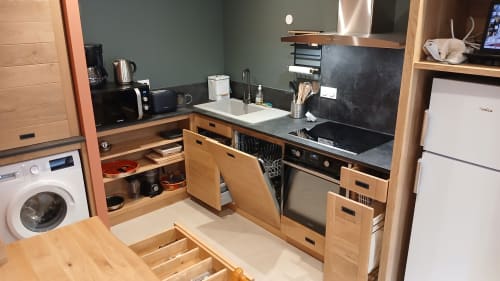 Compact kitchen at Les Ateliers du Moulin B&B in Poligny with wooden cabinets, black countertop, and modern appliances