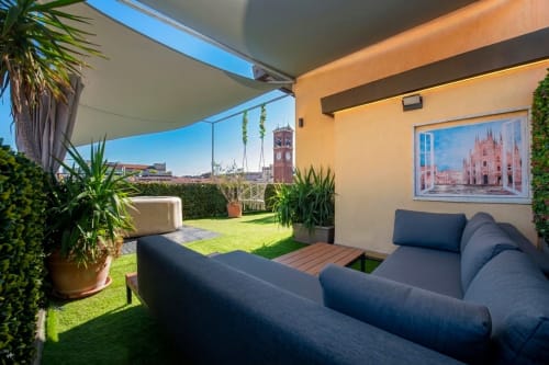 Spacious Milan apartment terrace with city views, comfortable seating, and lush greenery overlooking Navigli