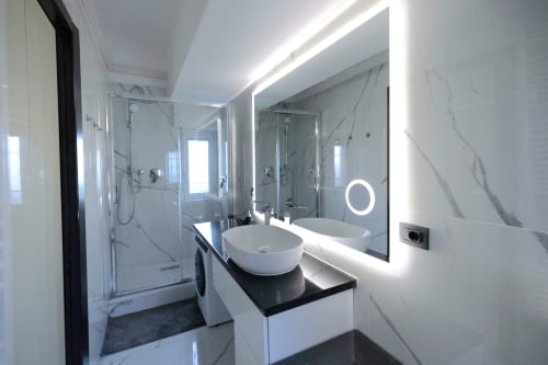 Modern bathroom in Milano apartment with dual sinks, LED mirror, marble tiles, and glass shower enclosure
